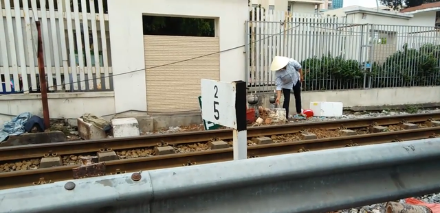 Một người bán hàng đun nước ngay bên đường ray tàu hỏa