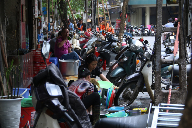 Trên phố Mã Mây một cửa hàng ăn uống nhân viên ngồi tràn ra vỉa hè để rửa bát.