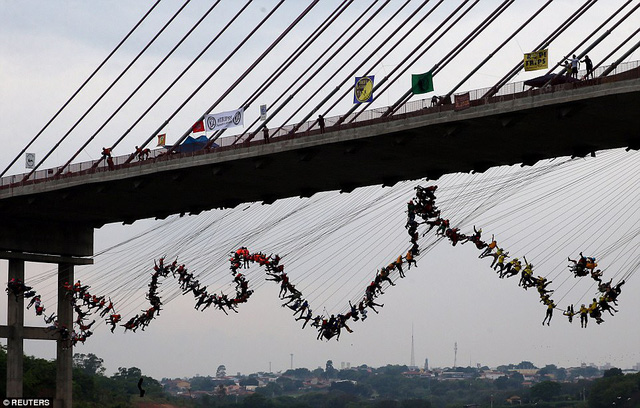 
Theo Dailymail, màn nhảy cầu tập thể diễn ra vào ngày 22/10 khi 245 người buộc dây thừng vào người, đội mũ bảo hiểm và cùng nhau lao xuống cây cầu cao gần 30m tại Hortolandia, gần Sao Paulo, Brazil.

