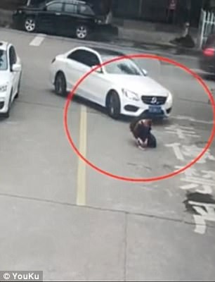 
Ảnh chụp từ clip cho thấy cậu bé ngồi buộc dây giày giữa đường
