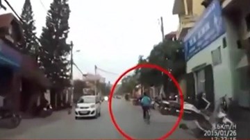 Vừa đạp xe, vừa múa hát, bé trai ngã nhào trước đầu ô tô