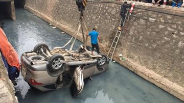 Người phụ nữ kẹt trong ô tô lật ngửa dưới mương thối