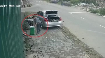 Người đàn ông đi ô tô trộm thùng rác bên đường