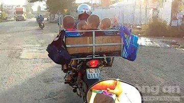 Người phụ nữ chở 4 trẻ em trong lồng sắt, chạy bon bon trên đường