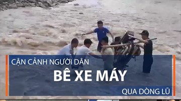 Người dân bê xe máy qua dòng lũ