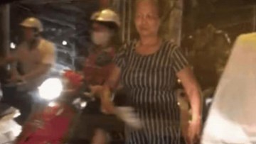 Tay cầm quạt phe phẩy, bác gái một mình phân làn cho cả con đường