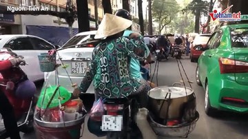 Người phụ nữ vô tư chở nồi nước đang sôi đi trên phố Sài Gòn