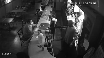 Người đàn ông bình tĩnh ngồi hút thuốc dù bị tên cướp dí súng vào người