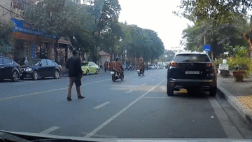 Người đàn ông thong thả đi bộ giữa đường bị xe máy tông từ phía sau