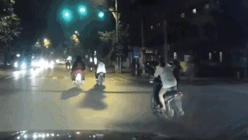 Hai cô gái thay người điều khiển khi xe máy đang chạy qua ngã tư