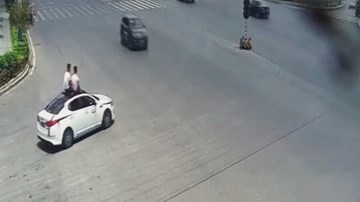Trời nóng, 2 người đàn ông ngồi trên nóc ô tô ‘chạy như bay’ để hóng gió