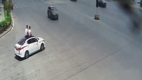 Trời nóng, 2 người đàn ông ngồi trên nóc ô tô ‘chạy như bay’ để hóng gió