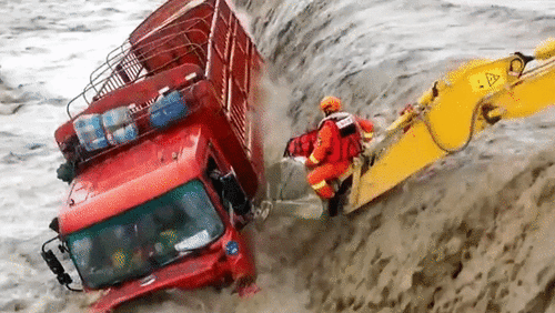 Dùng máy xúc giải cứu tài xế xe tải bị kẹt giữa dòng nước lũ